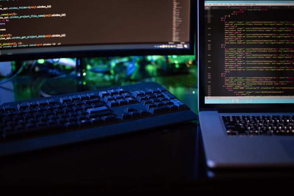Three computer screens with computer programming code